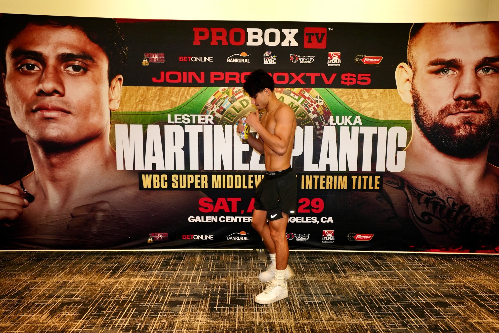 Amador Mendez posing in front of the Martinez vs Plantic fight poster